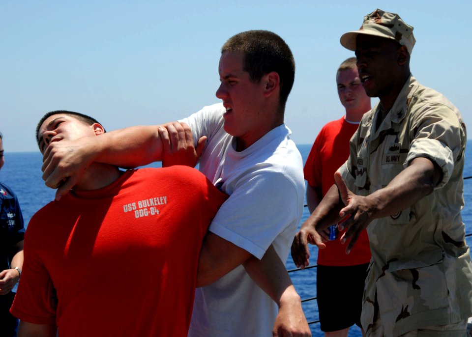 US Navy 080617-N-2838W-066 Boatswain's Mate Seaman John Vondrachek demonstrates essential restraint techniques while Master-at-Arms 1st Class Anwar Blakely critiques his actions during a force protection drill aboard the guided