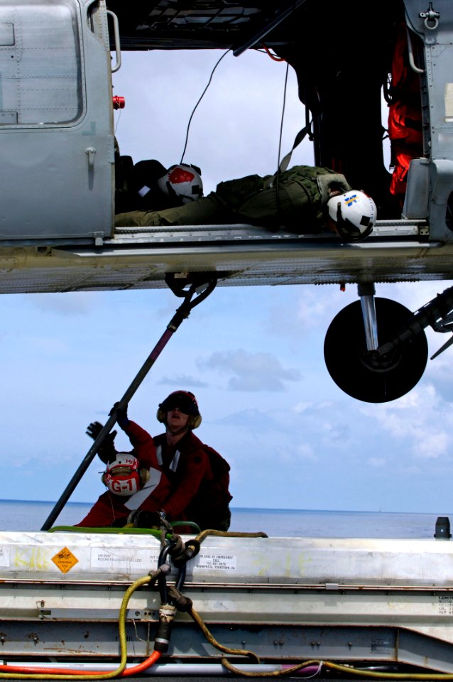 US Navy 080620-N-7883G-187 HSC-25 aviation warfare systems operators watch as Aviation Ordnanceman Airman Robert Campbell, right, and Aviation Ordnanceman Airman Abby Blair attach a cargo pennant to an MH-60S Seahawk on the fli