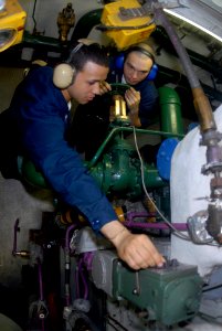 US Navy 080621-N-3946H-005 Engineman 2nd Class Andy Torres, left, of Brooklyn, N.Y., shows Engineman 3rd Class Jonathan Basely, of Seattle, how to adjust the speed of the number two emergency diesel engine