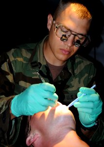 US Navy 080622-N-1120L-008 Lt. Matthew Dent, Naval Mobile Construction Battalion (NMCB) 7's dental officer, performs a dental exam on a Seabee during the battalion's unit field exercise (FEX) photo