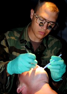 US Navy 080622-N-1120L-008 Lt. Matthew Dent, Naval Mobile Construction Battalion (NMCB) 7's dental officer, performs a dental exam on a Seabee during the battalion's unit field exercise (FEX)