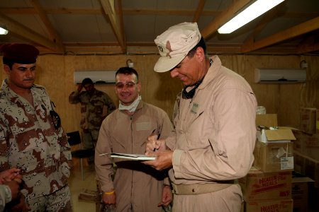 US Navy 080620-N-9623R-250 Lt. Scott Bender, from of Casa Grande, Ariz., signs paperwork that will turn over custody of a Naval Mobile Construction Battalion (NMCB) 17 builtman combat outpost located in the Iraqi desert to the