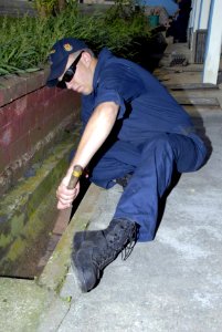 US Navy 080621-G-9409H-087 SINGAPORE (June 21, 2008) Boatswain's Mate 3rd Class Russell Hamm from the the guided-missile frigate USS Ford (FFG 54) cleans a drainage gutter during a community relations project