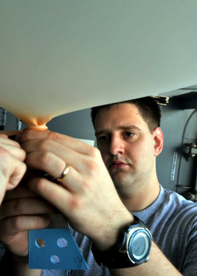 US Navy 080625-N-7981E-108 Aerographer's Mate 3rd Class Shane Green attaches a sensor package and transmitter to a weather balloon