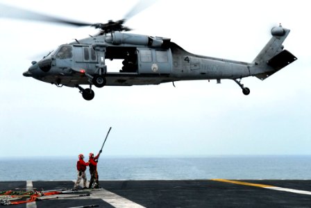 US Navy 080625-N-2610F-084 Flight Deck Gunner Chief Warrant Officer Eric Richmond, left, and Aviation Ordanceman 3rd Christopher Wozniak connect hoisting slings to an MH-60S Seahawk
