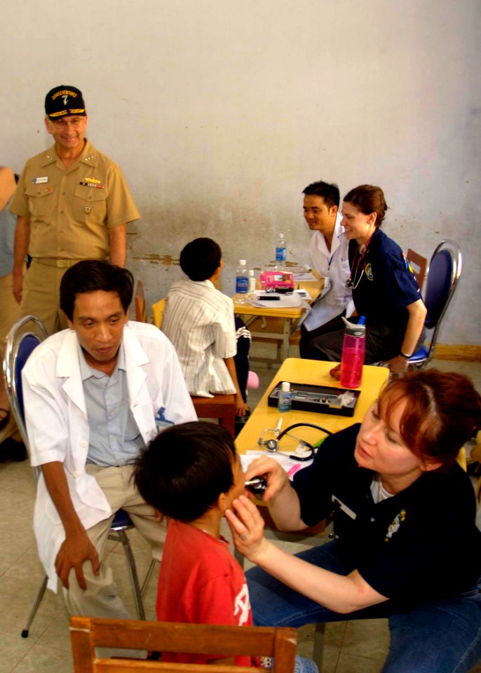 US Navy 080627-N-0209M-009 Vice Adm. Doug Crowder, commander, U.S. 7th Fleet, looks on as Cmdr. Rosemarie Tan performs an examination on a patient during a tour of the medical civic action program site