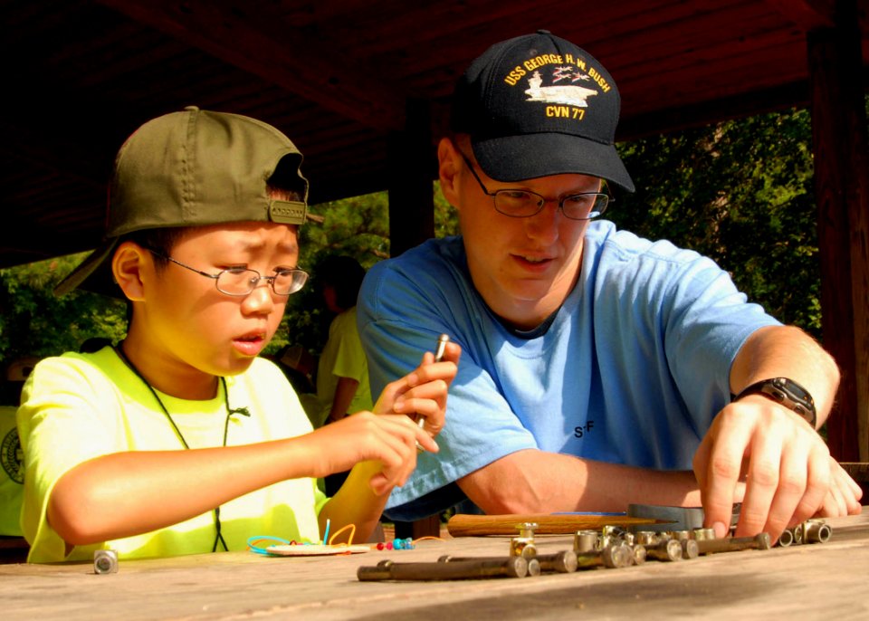 US Navy 080624-N-1981M-051 Aviation Boatswain Mate (Fuels) Airman Todd J. Losure, assigned to Pre-Commissioning Unit George H.W. Bush (CVN 77), helps a Cub Scout with leather stenciling during an arts and crafts class