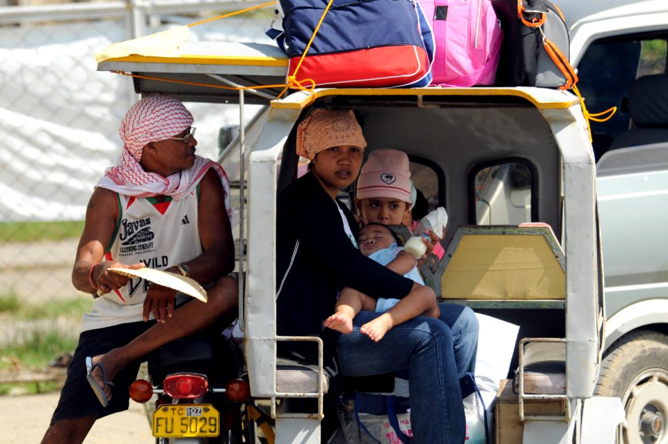 US Navy 080626-N-4009P-074 People sit outside the gates of the airport in Kalibo as supplies from the Nimitz-class aircraft carrier USS Ronald Reagan (CVN 76) arrive via helicopter