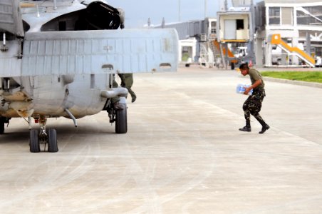 US Navy 080626-N-5961C-002 A member of the Philippine Army carries bottled water to a waiting helicopter assigned to Helicopter Anti-Submarine Squadron (HS) 4 at Iloilo airport