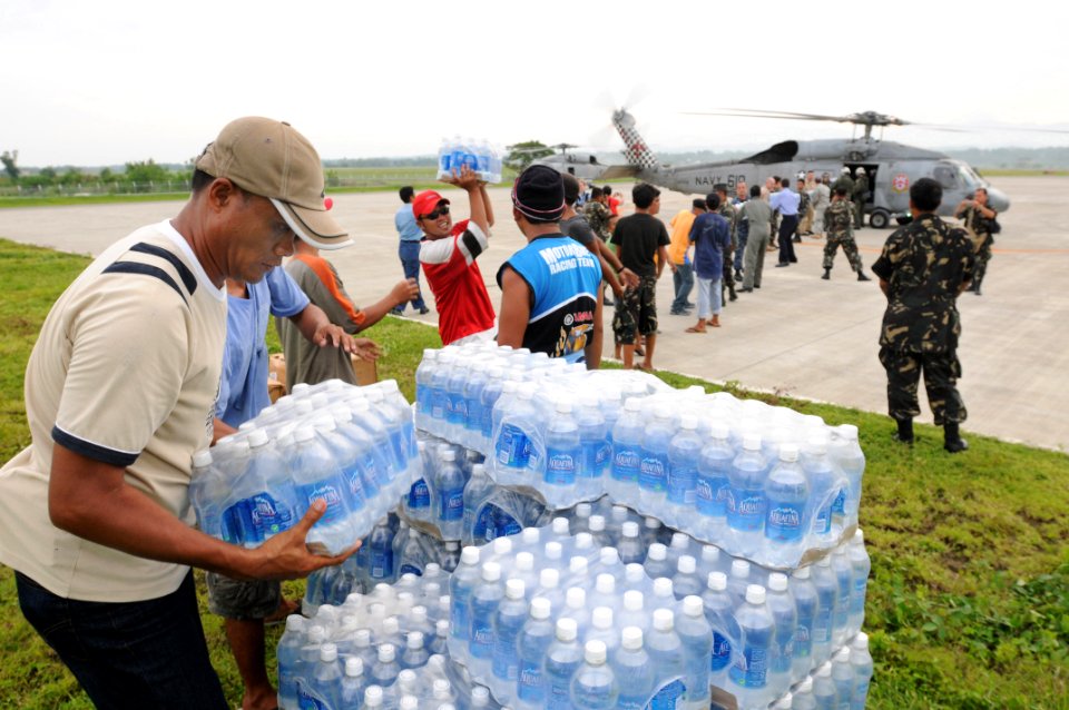 US Navy 080625-N-5961C-002 Residents of Iloilo help U.S. service members unload bottled water and rice from a helicopter assigned to the
