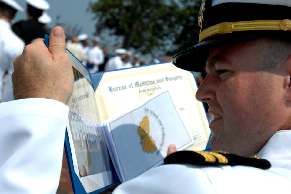 US Navy 080627-N-8148A-233 Lt. Thomas Thomas, from Norfolk, Va., tries to locate himself in a graduating class picture after the conclusion of Naval Medical Center Portsmouth intern class of 2008 graduation ceremony