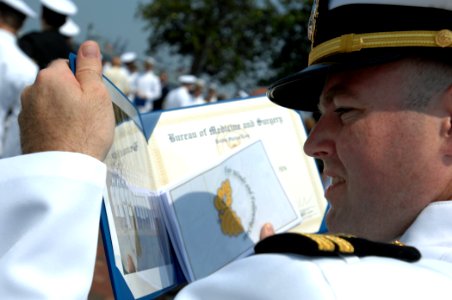 US Navy 080627-N-8148A-233 Lt. Thomas Thomas, from Norfolk, Va., tries to locate himself in a graduating class picture after the conclusion of Naval Medical Center Portsmouth intern class of 2008 graduation ceremony