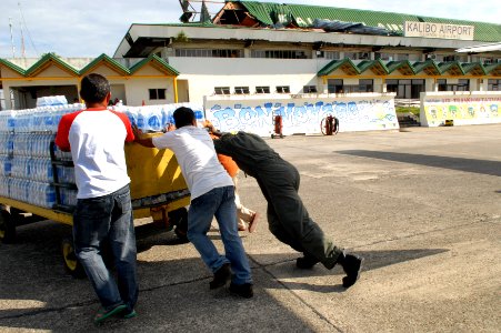 US Navy 080627-N-0640K-317 Aviation Structural Mechanic 2nd Class Myron Robertson, of Carson, Calif., helps local Philippine residents push a cart full of supplies at Kalibo Airport