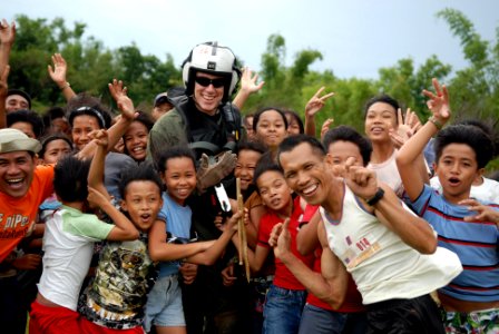 US Navy 080628-N-0640K-453 Aviation Warfare Systems Operator Airman John Baker poses for a photo with Alimodian residents after delivering relief supplies in the wake of Typhoon Fengshen