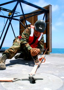 US Navy 080630-N-4973M-009 Seaman Rafael Garcia, assigned to Amphibious Construction Battalion (ACB) 1, secures a structural piece of the Navy Elevated Causeway System (ELCAS)