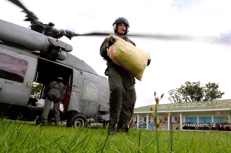 US Navy 080630-N-5961C-010 Aviation Warfare Systems Operator 2nd Class Travis Story, a native of Reading, Calif., carries a 100-pound sack of rice to a school in the remote village of Altavas