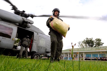 US Navy 080630-N-5961C-010 Aviation Warfare Systems Operator 2nd Class Travis Story, a native of Reading, Calif., carries a 100-pound sack of rice to a school in the remote village of Altavas