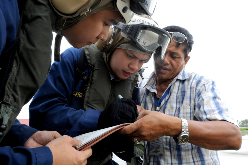 US Navy 080629-N-5961C-003 Chief Storekeeper Jep Rosario, Storekeeper 1st Class Lorenz Partosan and a villager from Kalibo begin to organize how they will receive thousands of liters of bottled water during a vertical replenish