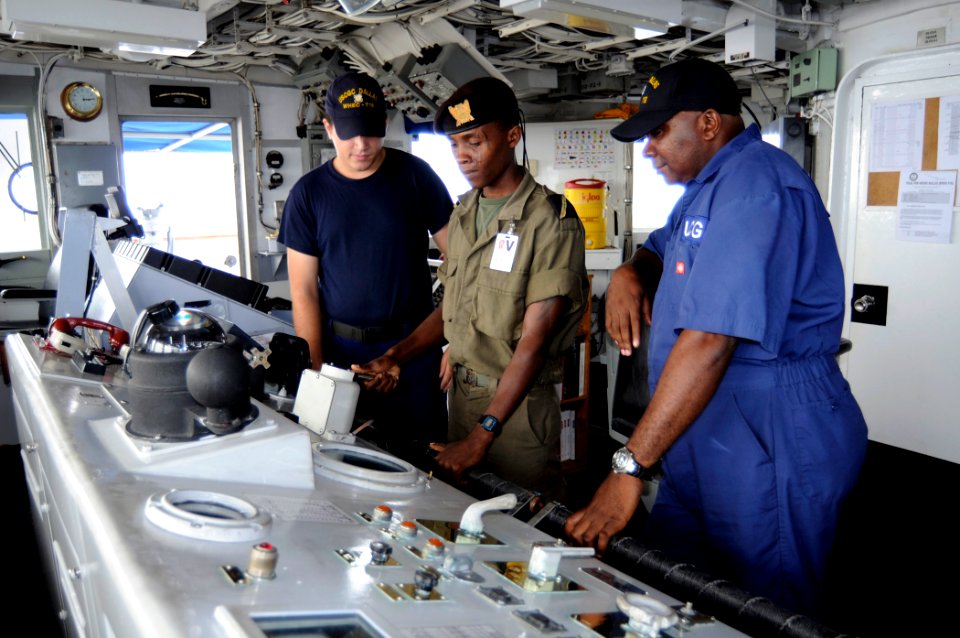 US Navy 080701-G-2443T-010 Seaman Eliud Ramos, a crewmember aboard the U.S. Coast Guard Cutter Dallas (WHEC 716), teaches Ens. Jimmy Tiny how to steer
