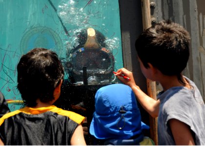 US Navy 080628-N-3560G-266 A Navy diver from Underwater Construction Team 2 plays tic-tac-toe with children from the inside of a water tank during Seabee Days photo