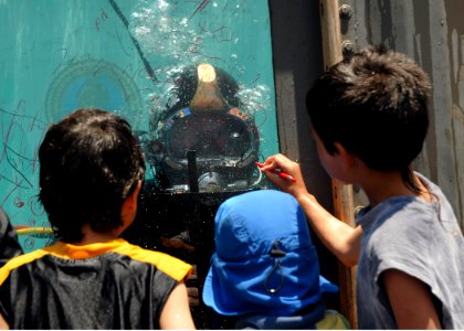 US Navy 080628-N-3560G-266 A Navy diver from Underwater Construction Team 2 plays tic-tac-toe with children from the inside of a water tank during Seabee Days
