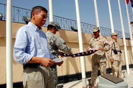 US Navy 080704-F-7045D-001 Retired Navy Cmdr. Joseph Agra III, left, the Afghan National Army Air Corps logistics mentor, reads a citation regarding an American flag with 48 stars that was raised during a ceremony July 4 at Cam photo