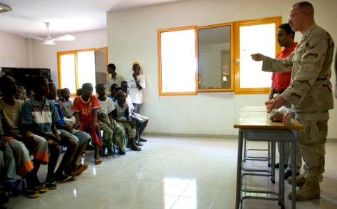 US Navy 080701-F-0986R-023 Cmdr. Michael Marks, a naval dentist with the Emergency Medical Unit at Camp Lemonier, Djibouti demonstrates to children the proper way to brush their teeth during a visit to a dental clinic in Djibou photo