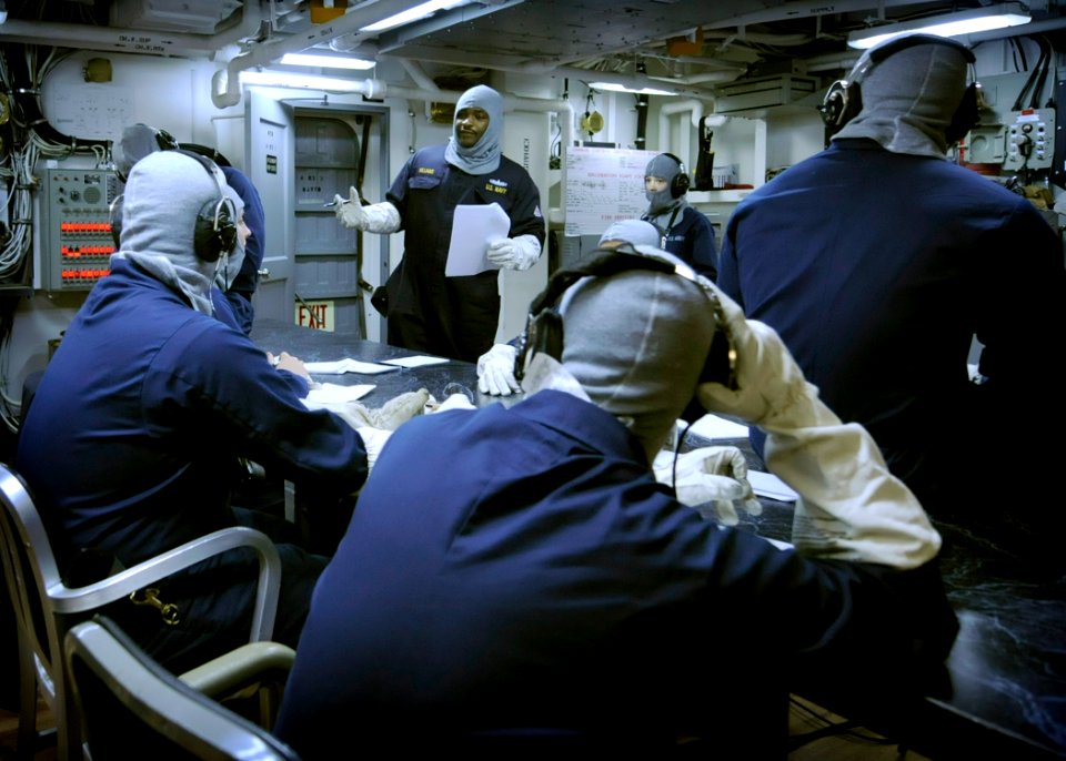 US Navy 080630-N-8546L-011 Chief Warrant Officer Will Williams uses a brief period of calm during a general quarters drill to mentor phone talkers in damage control (DC) central