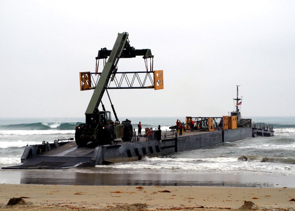 US Navy 080703-N-4973M-012 Seabees assigned Amphibious Construction Battalion (ACB) 1 offload a structural piece of an elevated causeway system onto Improved Navy Lighterage System (INLS) Causeway Ferry 1