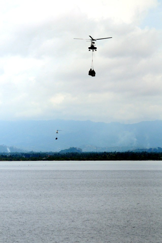 US Navy 080629-N-5961C-006 Super PUMA helicopters fly much needed bottled water to Kalibo, Republic of the Philippines from the deck of the Military Sealift Command combat stores ship USNS Niagara Falls (T-AFS 3)