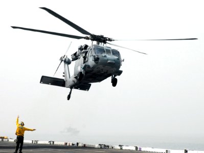 US Navy 080630-N-5148B-030 An Aviation Boatswains' Mate (Handling) guides an MH-60s Seahawk helicopter attached to the Helicopter Sea Combat Squadron 23 (HSC-23) to the drop off point on the flight deck