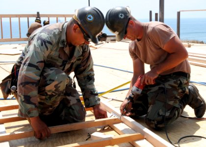 US Navy 080705-N-1424C-902 Construction Electrician 1st Class Samuel Roman and Builder 3rd Class Christopher Eyles, assigned to Amphibious Construction Battalion (ACB) 1 rebuild the deck of a platform overlooking Red Beach photo