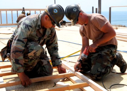 US Navy 080705-N-1424C-902 Construction Electrician 1st Class Samuel Roman and Builder 3rd Class Christopher Eyles, assigned to Amphibious Construction Battalion (ACB) 1 rebuild the deck of a platform overlooking Red Beach
