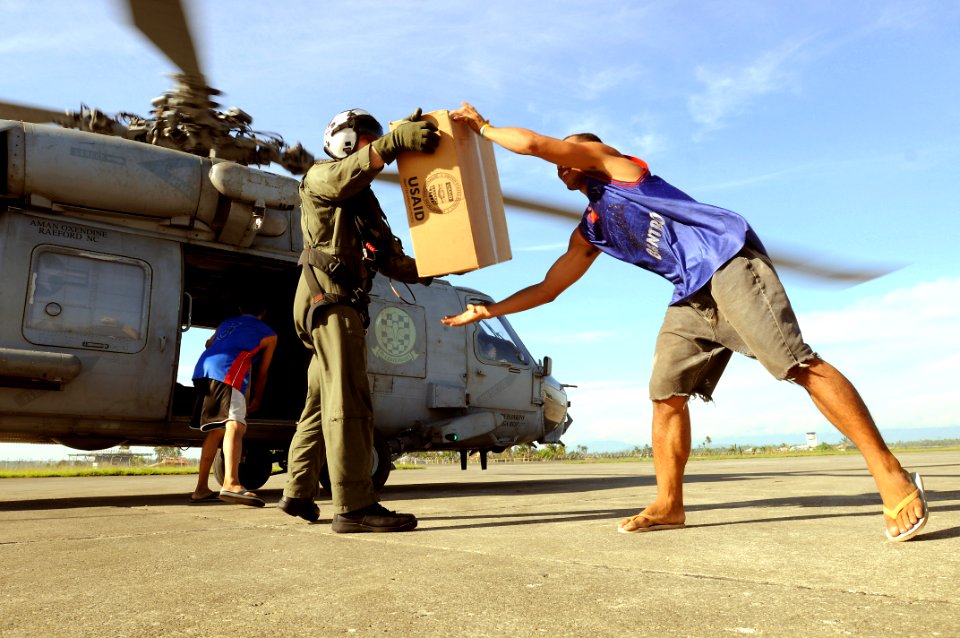 US Navy 080701-N-5961C-007 Aviation Warfare Systems Operator 2nd Class Slavek Glownia and a villager from Kalibo move a box of humanitarian supplies from an SH-60F Seahawk flown by members of Helicopter Anti-Submarine Squadron