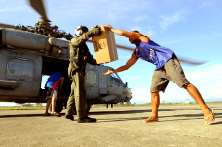 US Navy 080701-N-5961C-007 Aviation Warfare Systems Operator 2nd Class Slavek Glownia and a villager from Kalibo move a box of humanitarian supplies from an SH-60F Seahawk flown by members of Helicopter Anti-Submarine Squadron