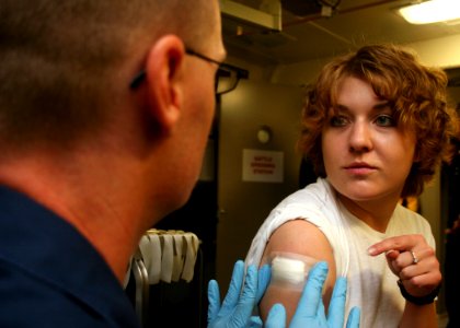 US Navy 080709-N-6764G-147 Seaman Lacey Bumstead, right, questions Hospital Corpsman 1st Class Steven Curran about her small pox vaccination aboard the amphibious transport dock ship USS San Antonio (LPD 17)