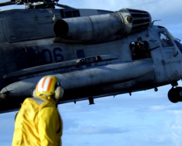 US Navy 080714-N-9500T-359 A landing signal enlisted looks on as a crew chief checks for obstructions after taking off from the amphibious assault ship USS Bonhomme Richard (LHD 6)