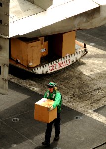 US Navy 080714-N-9898L-507 A Sailor assists in moving parcels from a C-2 Greyhound assigned to the