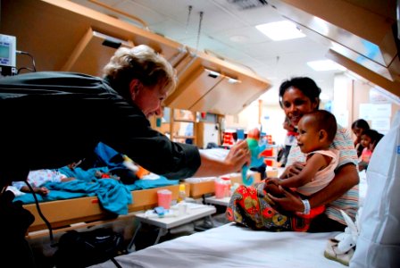 US Navy 080715-N-9689V-003 Donna Willard, wife of Adm. Robert Willard, commander of the U.S. Pacific Fleet, plays with a local Timorese child during a visit to the USNS Mercy (T-AH 19)