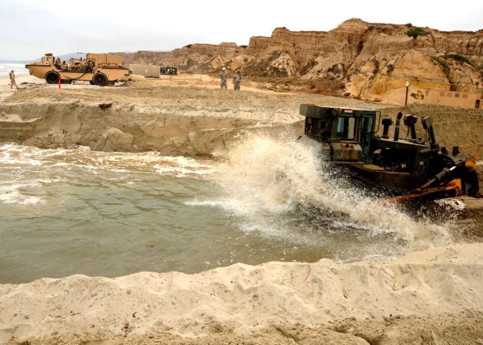 US Navy 080720-N-1424C-096 The force of the ocean crashes against the bulldozer as it digs a sand ramp at Gold Beach during Joint Logistics Over-The-Shore (JLOTS) 2008