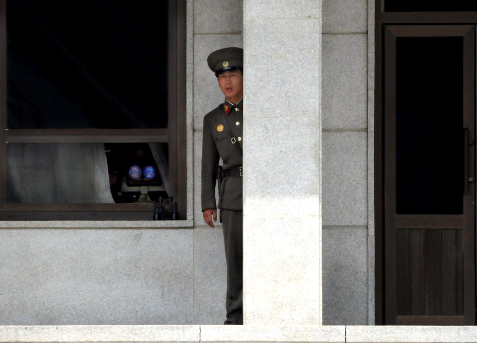 US Navy 080717-N-5961C-006 A Democratic People's Republic of Korea guard peers out from behind a granite pillar in North Korea to study the movements of Sailors from the Ronald Reagan Carrier Strike Group during a tour of the K