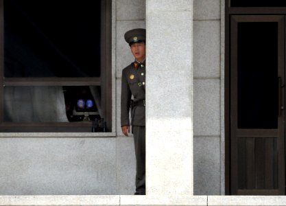 US Navy 080717-N-5961C-006 A Democratic People's Republic of Korea guard peers out from behind a granite pillar in North Korea to study the movements of Sailors from the Ronald Reagan Carrier Strike Group during a tour of the K