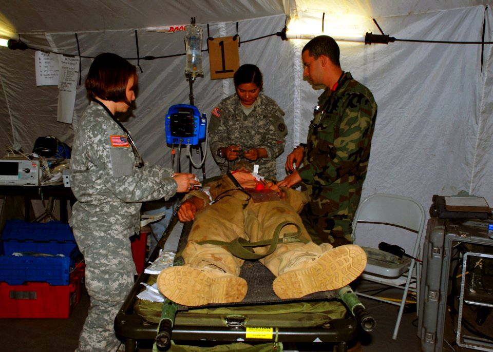 US Navy 080721-N-4973M-133 2nd Lt. Abby Delong, left, and Private 1st Class Christina Meyers, center, both assigned to the 396th Combat Support Hospital, treat a simulated patient's injuries