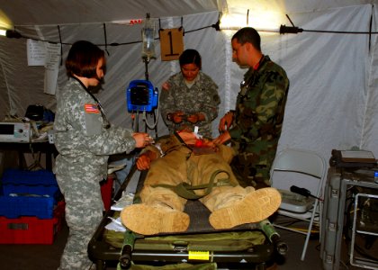 US Navy 080721-N-4973M-133 2nd Lt. Abby Delong, left, and Private 1st Class Christina Meyers, center, both assigned to the 396th Combat Support Hospital, treat a simulated patient's injuries
