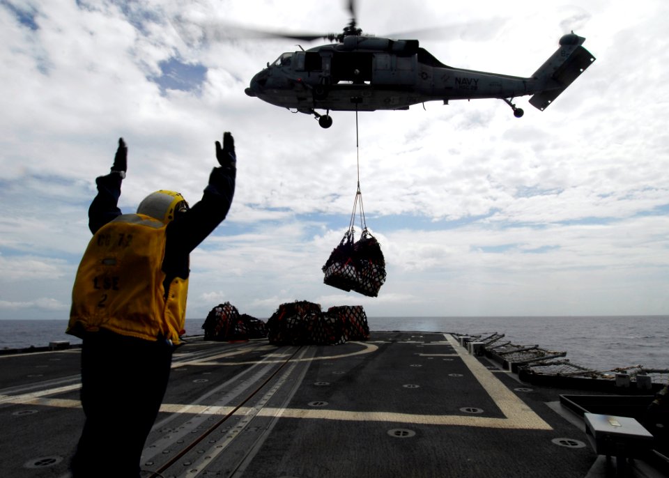 US Navy 080718-N-4236E-491 Boatswain's Mate 3rd Class Francisco Vega guides an MH-60S Seahawk from Helicopter Sea Combat Squadron 28 (HSC-28) bringing mail, supplies, and food aboard the guided-missile cruiser USS Vella Gulf (C