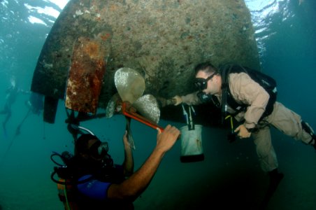 US Navy 080724-N-3093M-016 Senior Chief Diver Billy Gilbert, assigned to Mobile Diving and Salvage Unit (MDSU) 2, watches a member of the Saint Kitts and Nevis coast guard replace a propeller on a small patrol boat