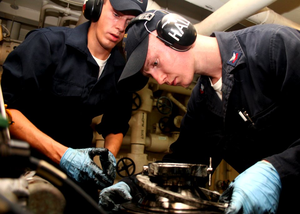US Navy 080725-N-6764G-089 Engineman Fireman Ryan Wright, left, and Engineman 2nd Class Tim Hall fasten a connector on a main engine lube oil purifier aboard the amphibious transport dock ship USS San Antonio (LPD 17)