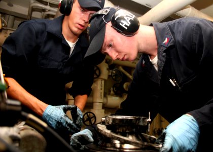 US Navy 080725-N-6764G-089 Engineman Fireman Ryan Wright, left, and Engineman 2nd Class Tim Hall fasten a connector on a main engine lube oil purifier aboard the amphibious transport dock ship USS San Antonio (LPD 17)