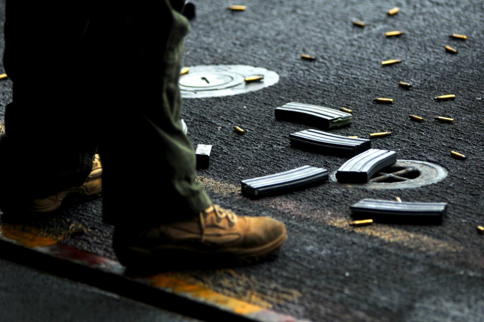 US Navy 080727-N-7981E-130 Spent shell casings and magazines lay at the feet of a member of helicopter visit, bard, search and seizure Team 2 during a live fire transition exercise aboard the Nimitz-class aircraft carrier USS A