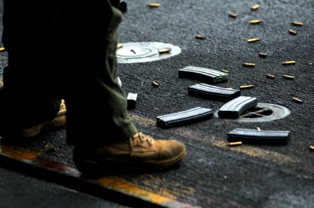 US Navy 080727-N-7981E-130 Spent shell casings and magazines lay at the feet of a member of helicopter visit, bard, search and seizure Team 2 during a live fire transition exercise aboard the Nimitz-class aircraft carrier USS A photo